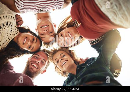 Fare piani sulla spiaggia. Ritratto ad angolo basso di un gruppo di amici in piedi in una tanghetta sulla spiaggia. Foto Stock