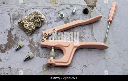 Set di prigionieri a pressione con pinze. Set per la foratura o il fissaggio di bottoni a pressione. Foto Stock