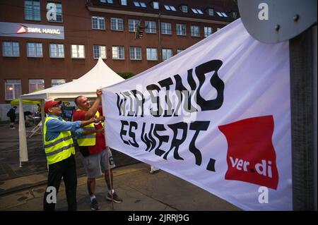 26 agosto 2022, Sassonia-Anhalt, Halle (Saale): Gli autisti di tram e i membri del sindacato Verdi piazzano uno striscione "We are Worth IT" all'ingresso del deposito di Hallesche Verkehrs AG a Freiimfelder Straße all'inizio dello sciopero di avvertimento. Gli scioperi di avvertimento nei trasporti pubblici locali in gran parte della Sassonia-Anhalt sono stati in pieno svolgimento il venerdì mattina. Verdi aveva chiesto gli scioperi di avvertimento perché non si poteva raggiungere un accordo dopo diversi cicli di negoziati nella controversia salariale con i datori di lavoro. Foto: Heiko Rebsch/dpa Foto Stock