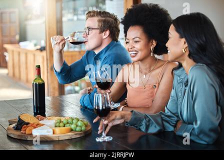 Festa del vino, amici e felice degustazione di lusso con frutta biologica sana con formaggio e alcol su un tavolo da pranzo. Sorriso, diversità e giovane gruppo di Foto Stock