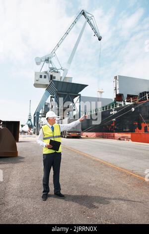 Responsabile logistica della catena di fornitura per la società di spedizione, le attrezzature di sicurezza e la gestione del carico. Successo aziendale, leader con casco che lavora in cantiere Foto Stock