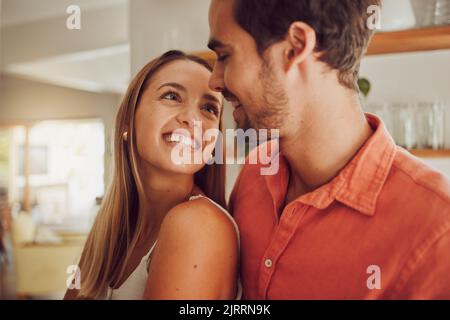 Coppia, sorridente e innamorato, avere un bel momento romantico in cucina a casa. Uomo e donna che trascorrono tempo libero affettuoso insieme, felice e. Foto Stock
