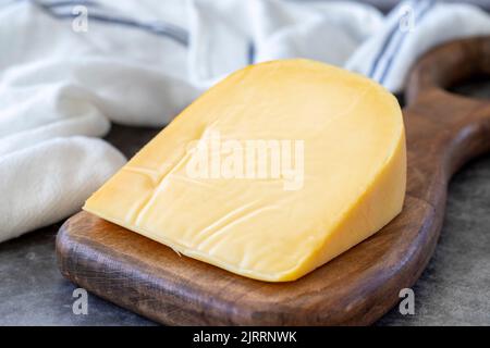 Formaggio gouda giallo. Formaggio gouda olandese duro, su fondo scuro. Primo piano Foto Stock