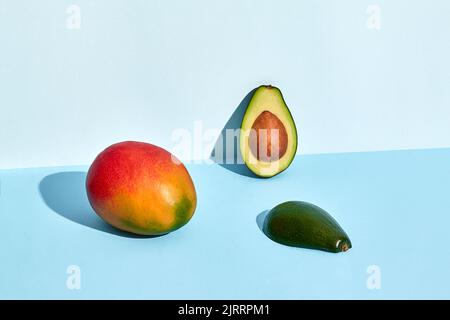 Avocado e frutti di mango su sfondo blu Foto Stock