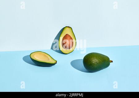 Tre metà di frutta avocado su sfondo blu Foto Stock