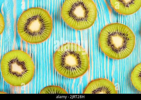 Fetta di kiwi fresco su sfondo di legno blu. Vista dall'alto, piatto. Foto Stock