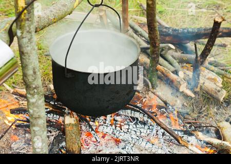 Due bollitori da turismo fumati sopra il fuoco del campo. Processo di cottura sulla natura. Vintage filtrato. Foto Stock