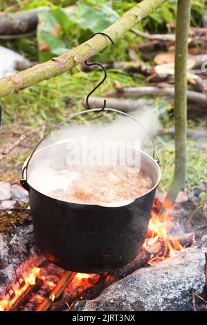 Due bollitori da turismo fumati sopra il fuoco del campo. Processo di cottura sulla natura. Vintage filtrato. Foto Stock