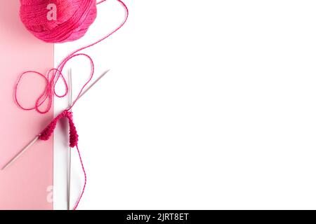 Palla rosa di lana con aghi per maglieria per maglieria abiti caldi con un posto per il testo. Giacitura piatta Foto Stock