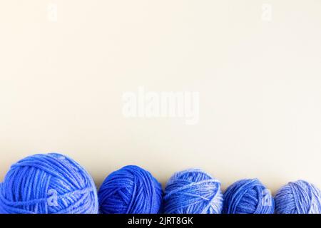 Palline blu di fili di maglia su sfondo giallo per lavorare a maglia abiti caldi Foto Stock