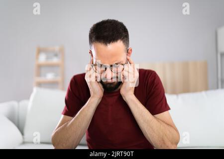 Forte rumore e dolore nell'orecchio dell'uomo Foto Stock