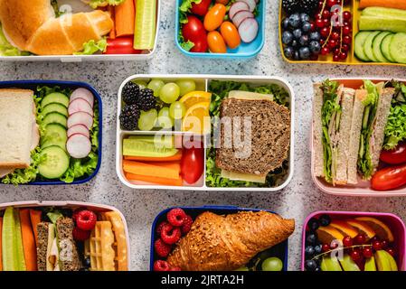 Shot di lunchboxes scuola con vari pasti nutrienti sani su sfondo di pietra Foto Stock