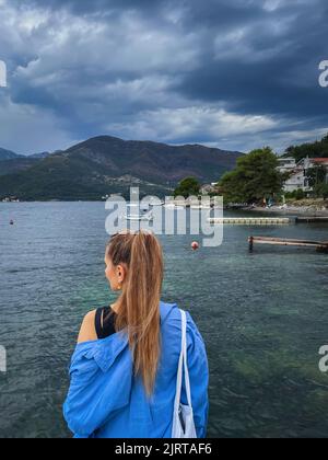 Donna che guarda il mare il giorno nuvoloso Foto Stock