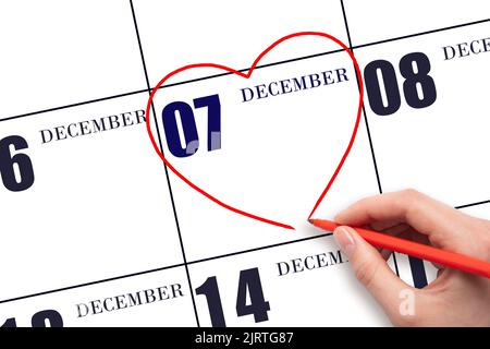 7th° giorno di dicembre. La mano di una donna che disegna una forma a cuore rosso alla data di calendario del 7 dicembre. Il cuore come simbolo dell'amore. Mese invernale. Giorno del Foto Stock