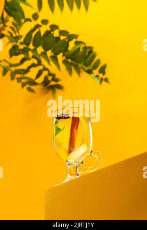 Teacup con delizioso tisana con agrumi, limoni, zenzero e menta isolato su sfondo giallo Foto Stock