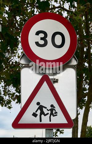 Segnale di pericolo zona scuola e segnale di traffico limite di velocità 30 Foto Stock