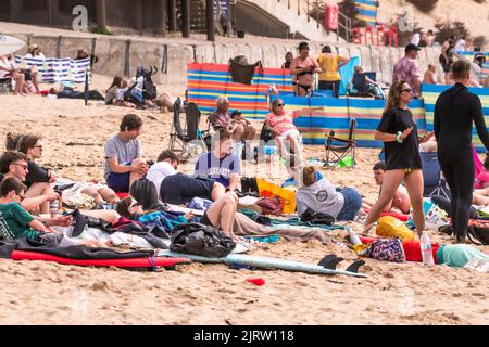 Un grande gruppo di giovani che si rilassano sulla Fistral Beach a Newquay in Cornovaglia nel Regno Unito. Foto Stock