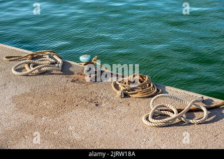 Primo piano di un arrugginito ormeggio con corde o falchi sul molo del porto. Golfo di la Spezia, Liguria, Italia, Europa. Foto Stock