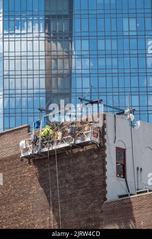 Lavoratori edili in alto sopra una strada urbana a New York City in un paniere sospeso, Midtown Manhattan, USA 2022 Foto Stock