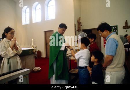 Sacerdote che dona comunione alla Messa coreana Chiesa cattolica di Sant'Anna Kingston Inghilterra Foto Stock