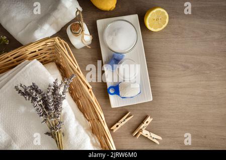 Concetto di lavaggio degli abiti con asciugamani e prodotti su tavolo in legno. Vista dall'alto. Composizione orizzontale. Foto Stock