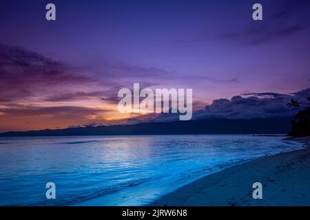 La luce blu del mattino presto durante l'alba proietta un tono di acqua nell'acqua mentre il sole inizia a infrangere le nuvole. Foto Stock