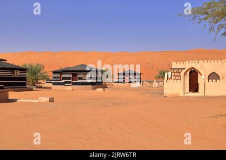 Campeggio in stile beduino accanto ad una enorme duna di sabbia nel deserto di Wahiba Sands in Oman. Foto Stock