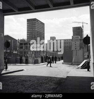 1960s, storico, persone che guardano giù su un muro a nuovi alti blocchi di uffici in costruzione all'angolo di Moor Lane e Ropemaker Street, Londra, EC2, Inghilterra, Regno Unito. Un segno per i costruttori Laing può essere visto. Foto Stock