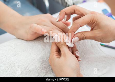 latina manicure eseguire una corretta pulizia delle unghie con un bastoncino di cotone, rimuovendo l'umidità in eccesso e il liquido sul chiodo. donna imparare a pulire n Foto Stock