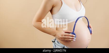 Donna incinta che suona musica al suo bambino. Si prende cura di lui. Foto Stock