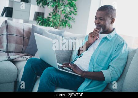 Foto di uomo anziano mentale manager capo seduta divano utilizzare netbook analizzare i colleghi relazione tempo di blocco in casa moderna Foto Stock