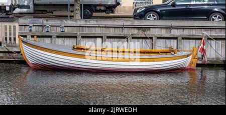 Elegante barca a vela in legno con bandiera danese ormeggiata su un canale a Copenhagen Danimarca Foto Stock