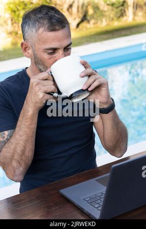 Bell'uomo che lavora sul suo computer portatile nel cortile di casa Foto Stock