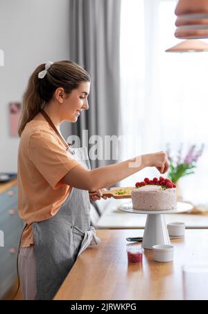 donna che cucinano il cibo e che cuoce in cucina a casa Foto Stock