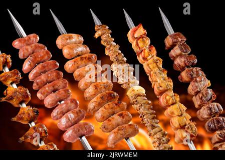 Spiedini brasiliani per barbecue. Cosce di pollo, salsiccia di manzo, salsiccia di pollo, cuore di pollo, pollo e manzo con pancetta. Foto Stock