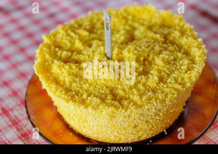 Corn couscous su tavola con tovaglia rossa e bianca. Piatti popolari della regione nord-orientale del Brasile, ampiamente consumati per la colazione. Foto Stock