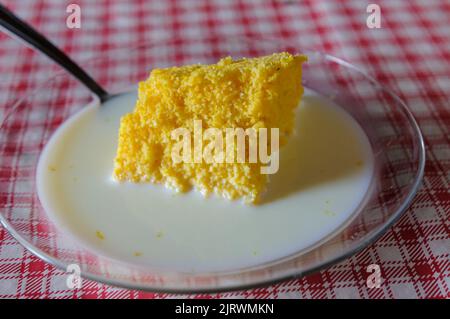 Corn couscous con latte su tavola con tovaglia rossa e bianca. Piatti popolari della regione nord-orientale del Brasile, ampiamente consumati per la colazione. Foto Stock