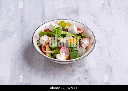 Una ciotola di insalata greca isolata su uno sfondo grigio di legno Foto Stock