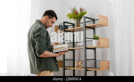 uomo con libri che decorano la casa e la mensola di disposizione Foto Stock