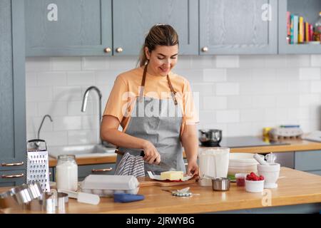 felice giovane donna che cucinava cibo in cucina a casa Foto Stock