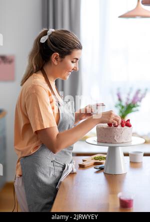 donna che cucinano il cibo e che cuoce in cucina a casa Foto Stock