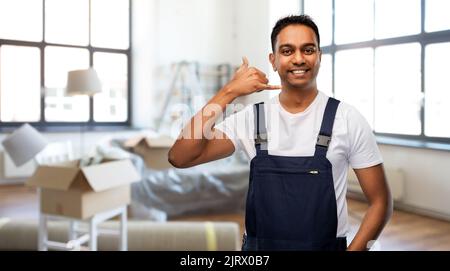 un lavoratore felice che effettua un gesto di chiamata in una nuova casa Foto Stock