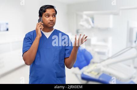 medico indiano che chiama al telefono presso l'ufficio dentistico Foto Stock
