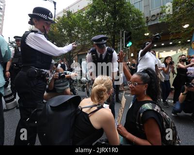 La polizia parla con i manifestanti fuori dalla sede centrale di Ofgem a Canary Wharf London. OFGEM ha confermato un aumento del 80,06% del tetto massimo dei prezzi dell'energia, inviando la bolletta media annuale della famiglia da 1.971 GBP a 3.549 GBP da ottobre. Data immagine: Giovedì 25 agosto 2022. Foto Stock