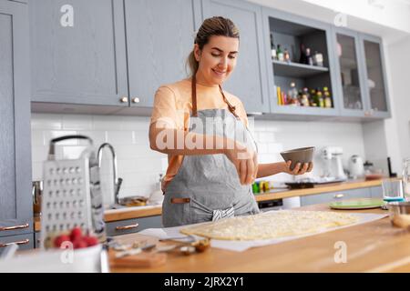 donna che cucinano il cibo e che cuoce in cucina a casa Foto Stock