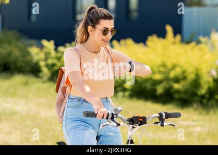 donna con orologio intelligente in bicicletta in città Foto Stock