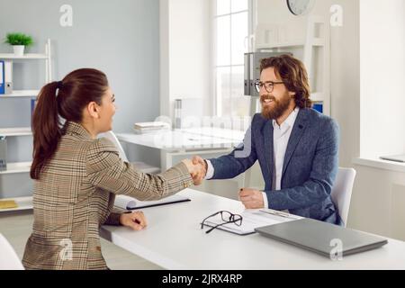 Buon agente di affari e cliente che fanno l'accordo, sorridendo e scambiando i handshakes Foto Stock