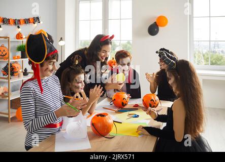 Insegnante di arte e artigianato e bambini in costumi di Halloween spettrale divertirsi in classe Foto Stock