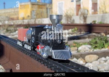 Immagine di un trenino giocattolo che corre su un binario reale in una stazione ferroviaria Foto Stock