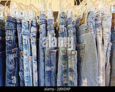 fila di jeans blu sbiaditi appesi su una scaffalatura del negozio Foto Stock